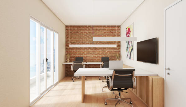 Front view of small office space, with wood floors, brick walls and laptops